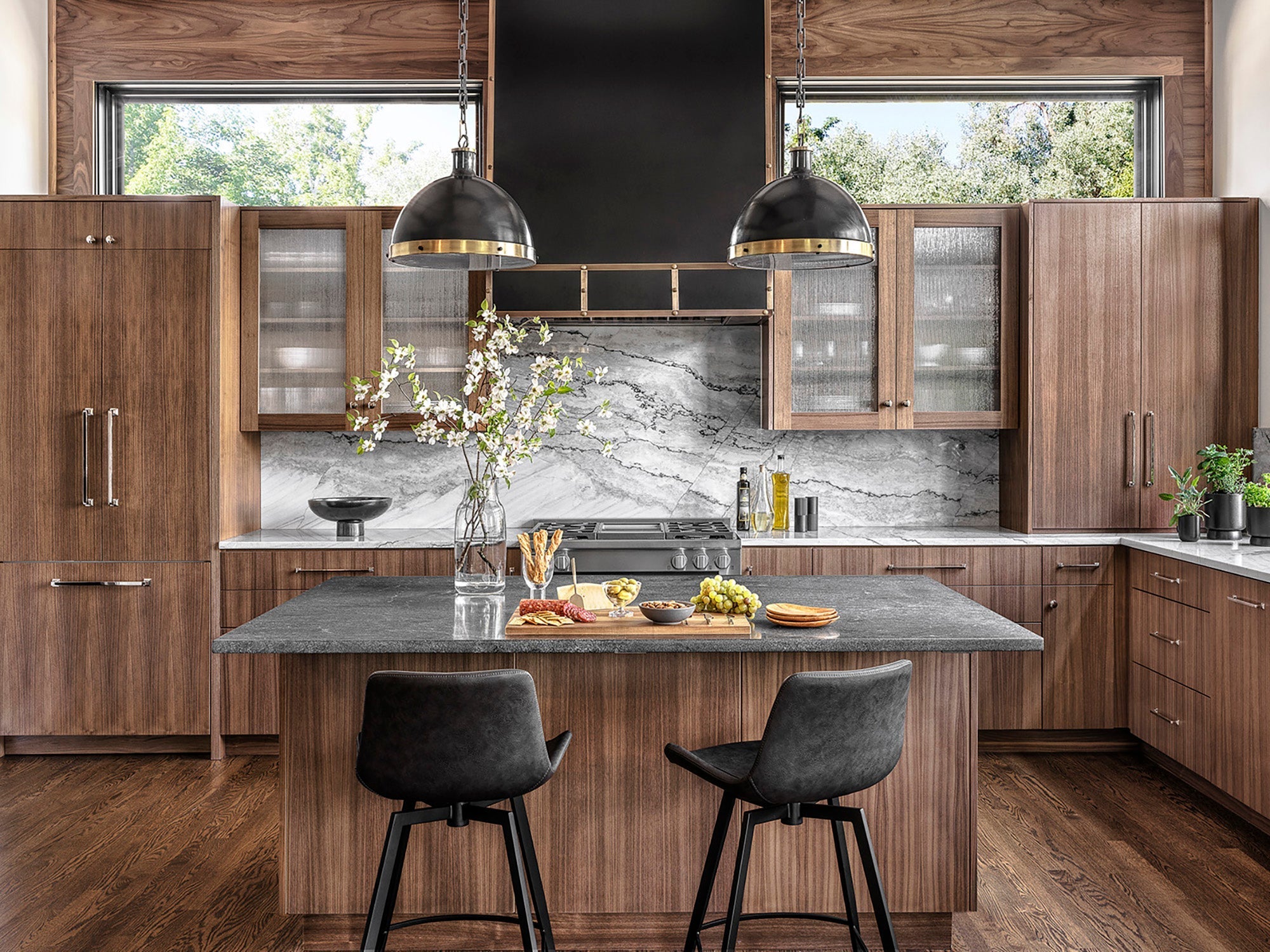 Metropolitan Mix kitchen with modern dark wood cabinetry, gray stone island, light gray backsplash, and black accents designed by Ättlingar.