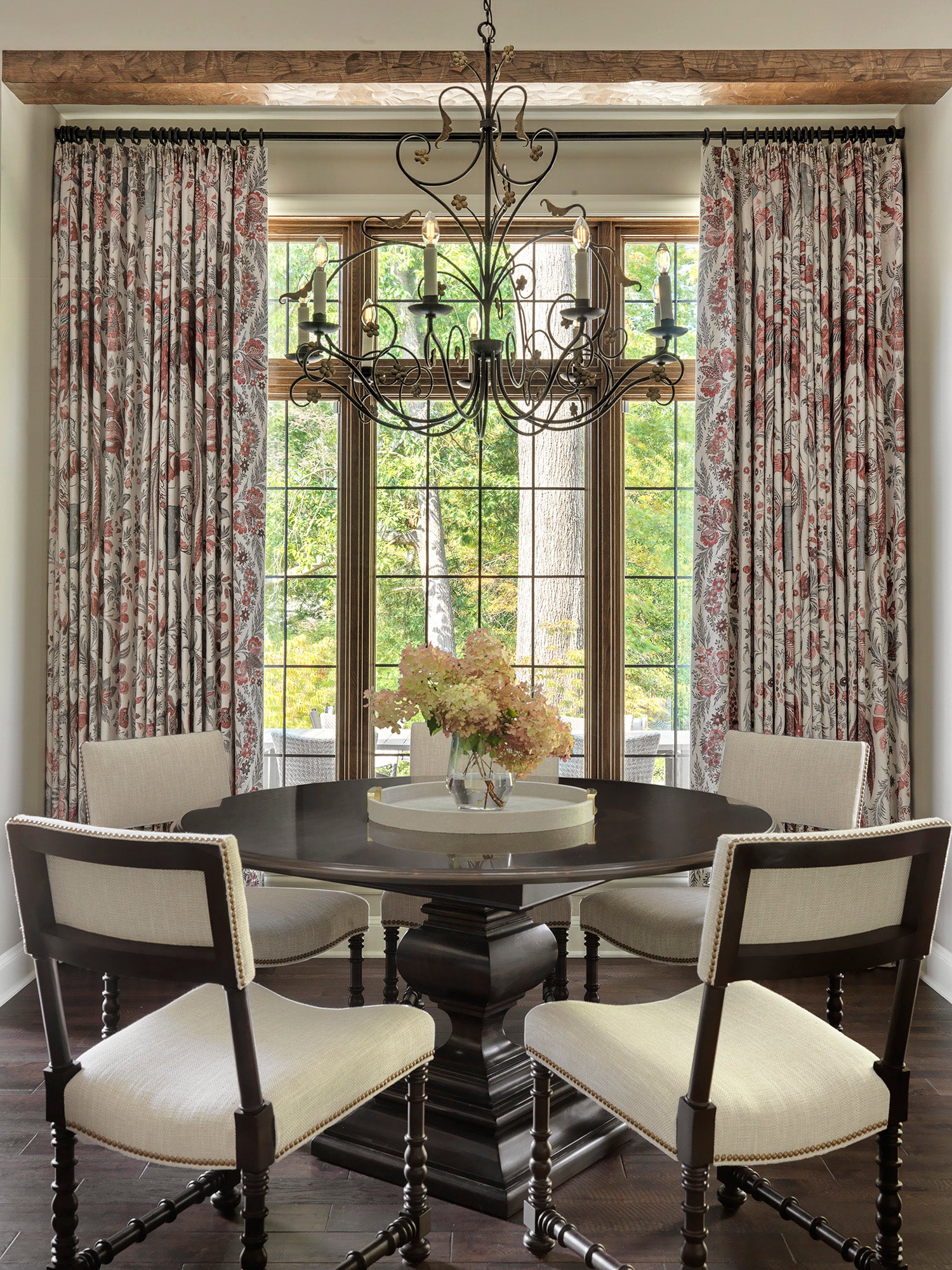 Dining room at 1920s Clayton Estate with carved pedestal table, white chairs, patterned drapery, chandelier, and expansive window views — timeless design by Ättlingar.