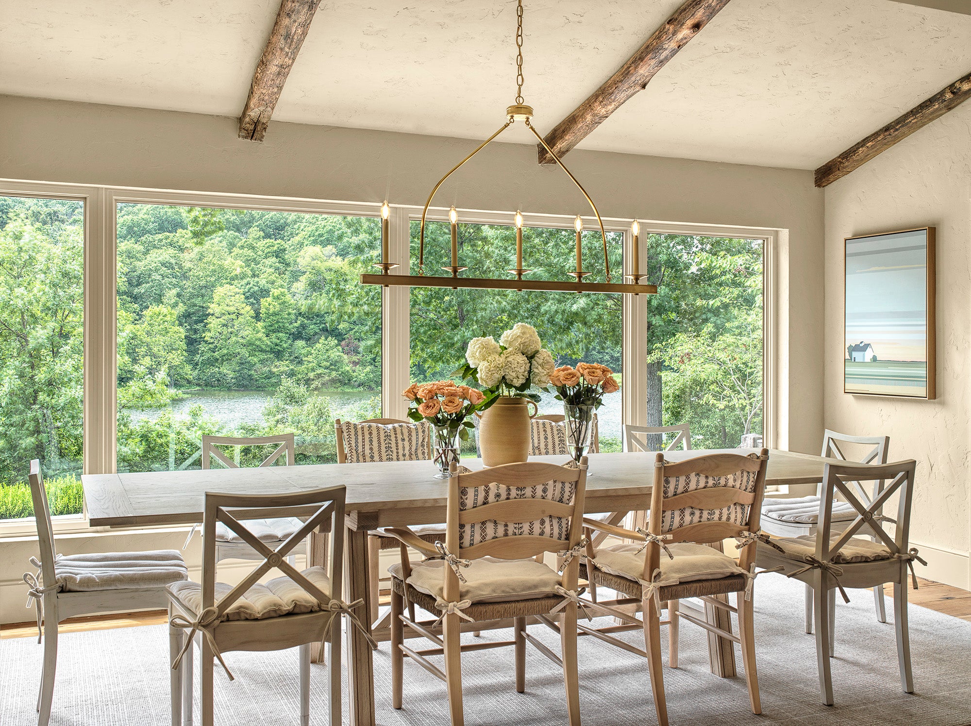 Light-filled rustic dining room with elegant wood chairs, oversized windows overlooking lush greenery, and timeless design by Ättlingar.