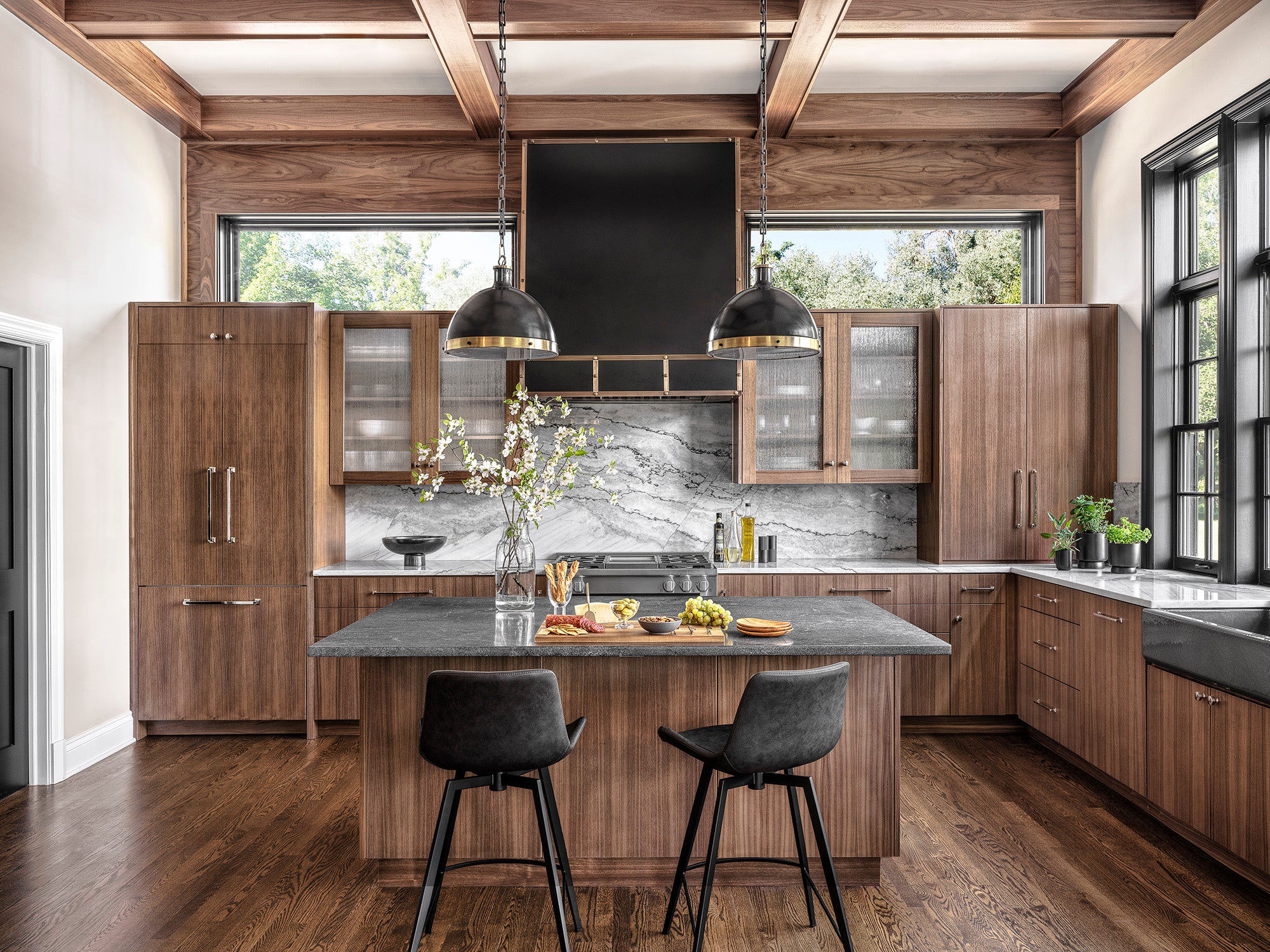 Metropolitan Mix kitchen with modern dark wood cabinetry, gray stone island, light gray backsplash, and black accents designed by Ättlingar.